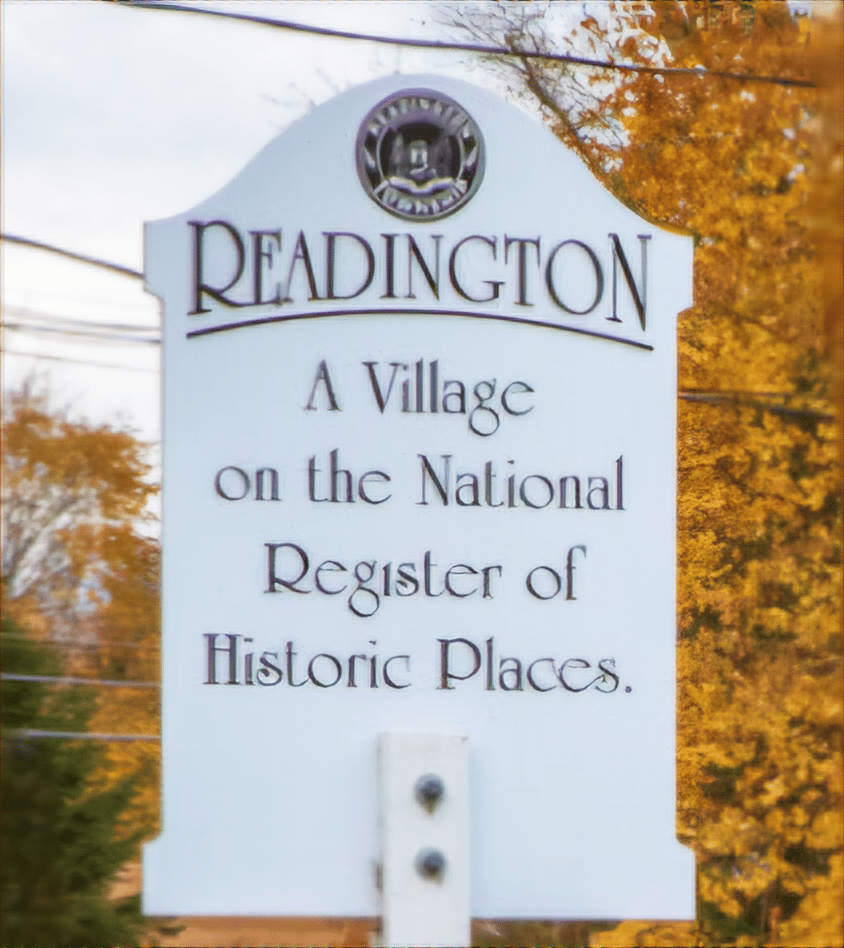 Sign with the words "Readington a village on the national register of historic places". The sign is flanked with autumn leaves.